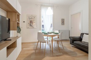 A modern living room with a dining area, a television on a wooden shelf, and a framed artwork on the wall. - CASA GIULIETTA - Sanremo (Sanremo)