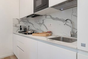 A modern kitchen with a marble backsplash, stainless steel sink, and a built-in microwave.