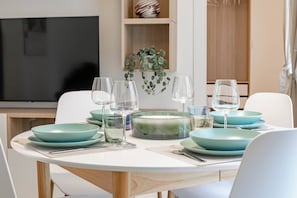 A dining area with a round table set for four, featuring teal plates and clear glassware. - CASA GIULIETTA - Sanremo (Sanremo)