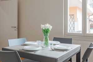 A dining table set with plates, cutlery, and glasses, with a vase of white flowers in the center. - CASA MERIDIANA - Centro - Sanremo (Sanremo)