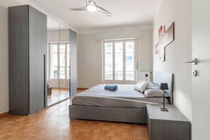 A bedroom with a bed, bedside table, lamp, wardrobe, and a large mirror. - CASA MERIDIANA - Centro - Sanremo (Sanremo)