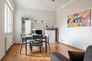 A modern living room with a dining area, a fireplace, and a large abstract painting on the wall.