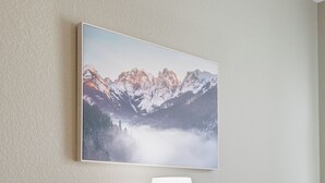 Et værelse med et bjerglandskabsmaleri, en bordlampe og to grønne polstrede lænestole.
