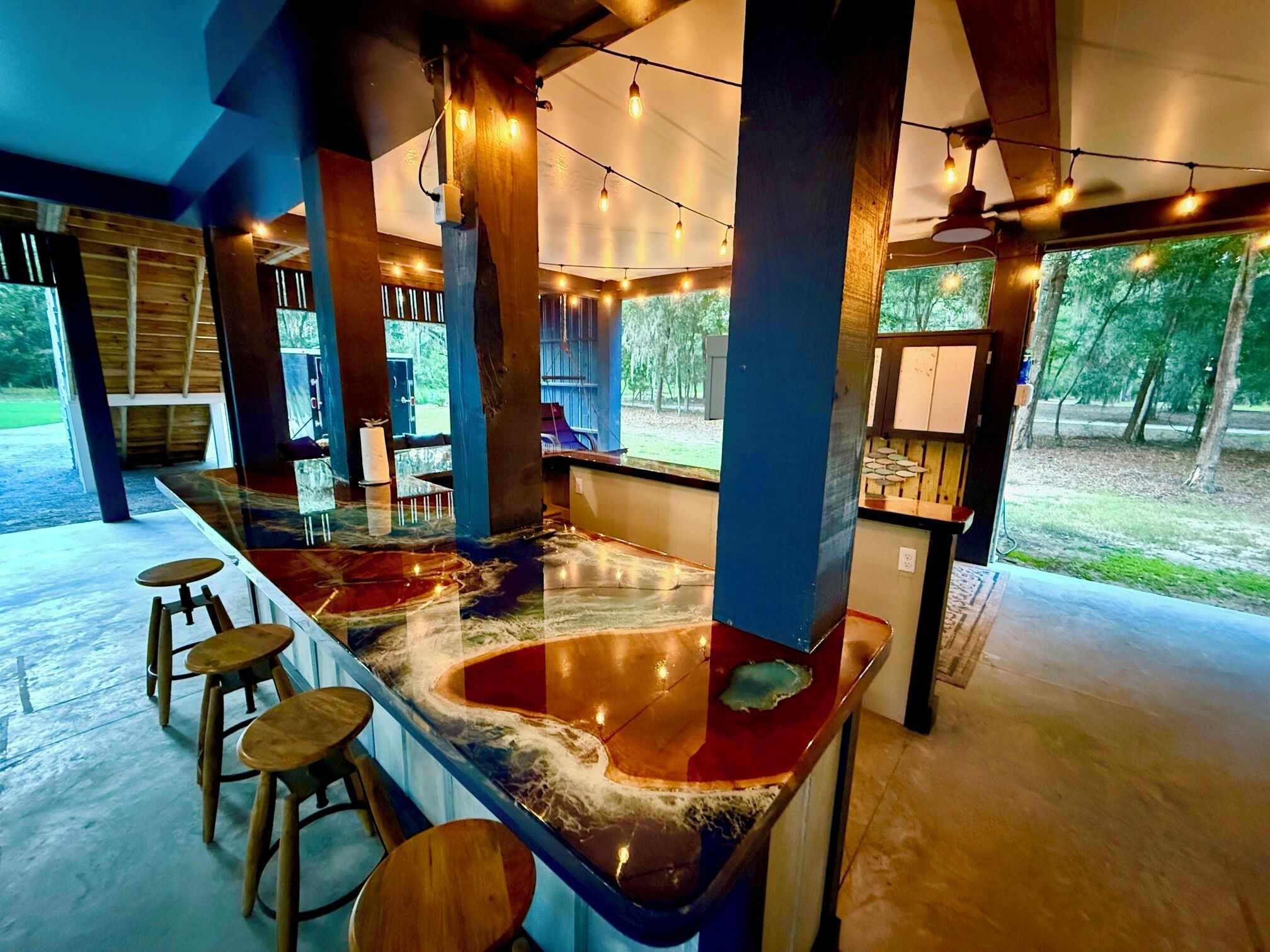 A bar area with a marble countertop, stools, and string lights.