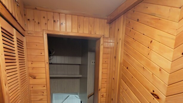 Un couloir étroit en bois, avec une porte donnant sur une pièce.