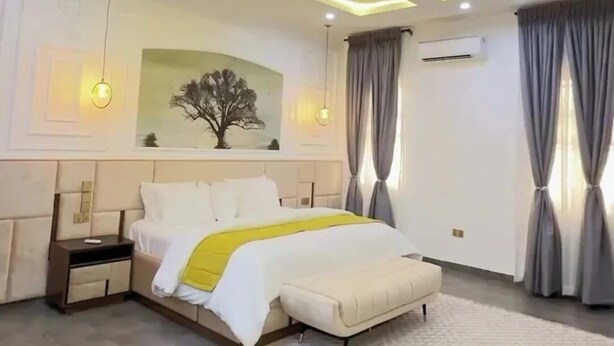 Un dormitorio moderno con una cama, mesitas de noche, una alfombra grande y un aire acondicionado instalado en la pared.