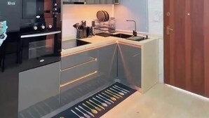 Una cocina moderna con horno empotrado, un lavamanos y una puerta de madera.