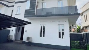 Un moderno edificio residencial de dos pisos, con balcón, ventanas amplias y techo plano.