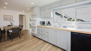 A modern kitchen with light grey cabinets, a wooden countertop, and a dishwasher. - The Coastal Retreat, Scenic Harbor, Ocean Views, Walk to Beach, Restaurants (El Granada)