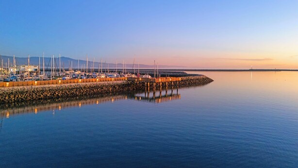 A marina with boats docked along a pier, calm water, and a clear sky. - The Coastal Retreat, Scenic Harbor, Ocean Views, Walk to Beach, Restaurants (El Granada)