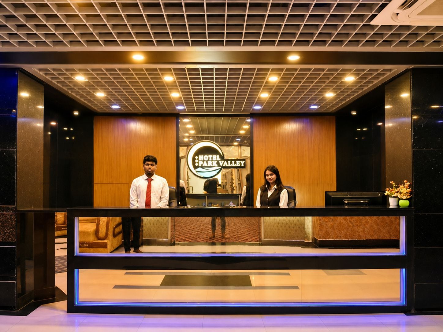 A reception desk with a sign reading 'Hotel Park Valley' and a modern ceiling design.