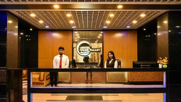 A reception desk with a sign reading 'Hotel Park Valley' and a modern ceiling design.