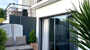 A modern outdoor living space with a sofa, a small table, and a potted plant.