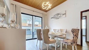 A dining area with a wooden ceiling, a table set for four, and a view of the outside through large windows. - Villa Magn lia by Atlantic Holiday (Machico)