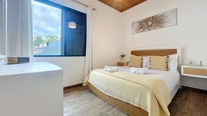 A bedroom with a bed, bedside tables, a window, a ceiling light, and a wall art piece. - Villa Magn lia by Atlantic Holiday (Machico)