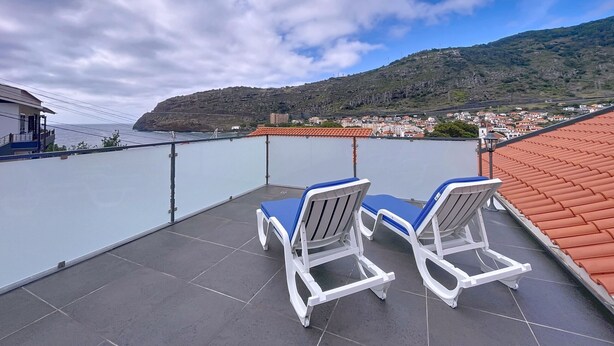 A terrace with two white lounge chairs and a view of a coastal town and mountains. - Villa Magn lia by Atlantic Holiday (Machico)