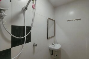 Een badkamer met douche, wastafel en spiegel.