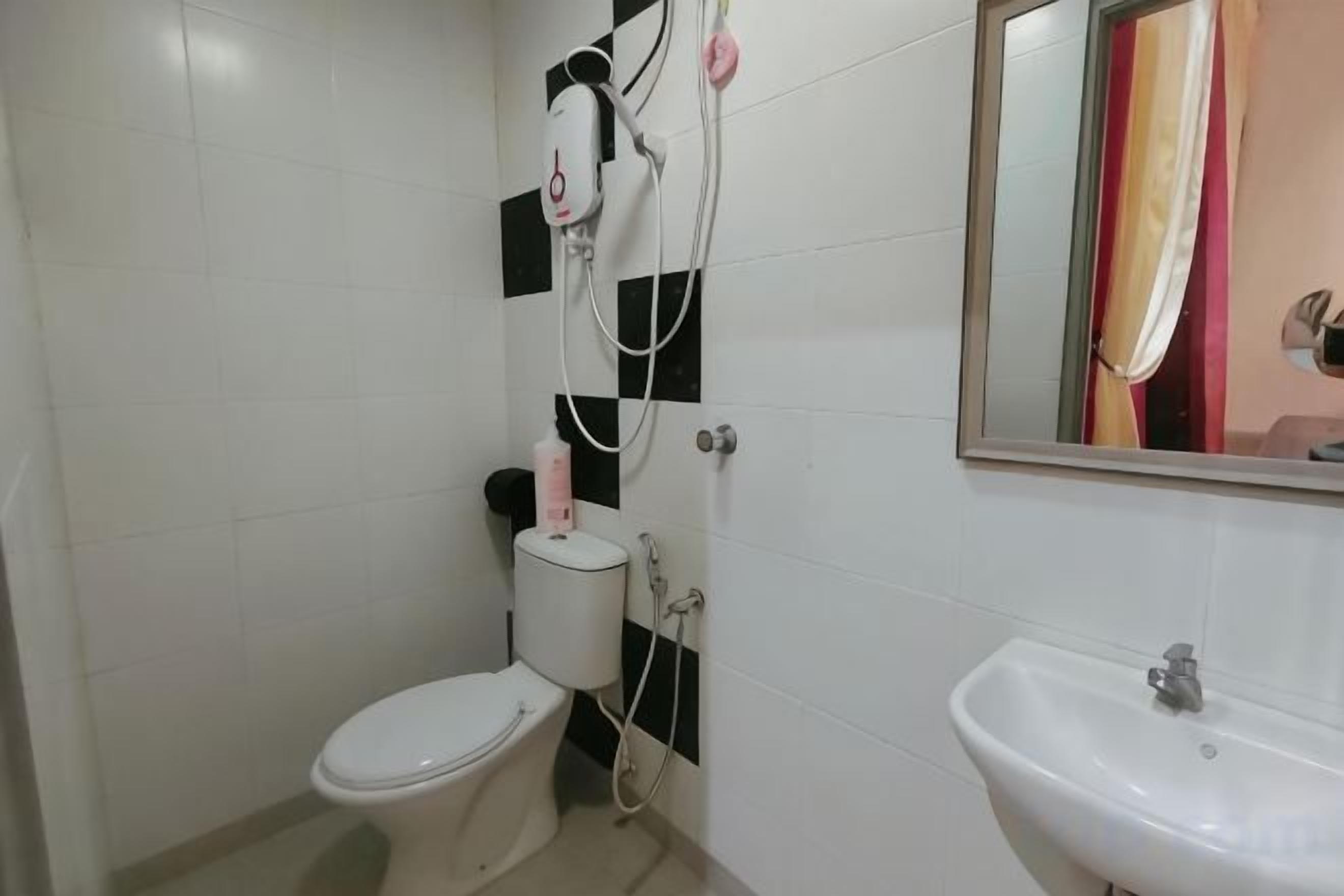 A bathroom with a toilet, a sink, and a shower with a mirror above the sink.