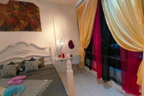 Een slaapkamer met een bed, een bureau en een raam met gordijnen.