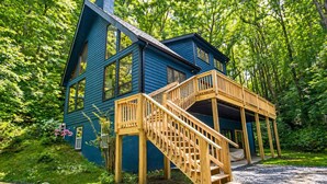 Une cabane bleue avec un escalier en bois menant à un porche abrité.