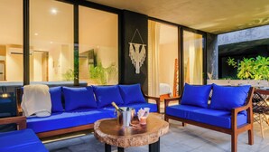 A modern outdoor seating area with blue cushioned sofas and a wooden coffee table. - 2-bedroom condo in enchanting Tulum with AC (Tulum)