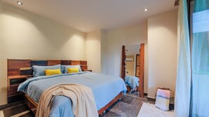 A modern bedroom with a large bed, wooden headboard, and a view of the outside through a window with curtains. - 2-bedroom condo in enchanting Tulum with AC (Tulum)