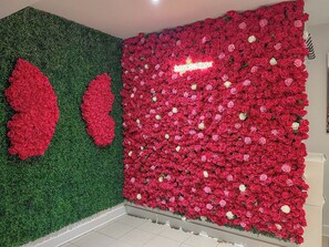 A room with a green wall and a large floral arrangement on the right. - L'évasion : Jacuzzi & Sauna (Tassin-la-Demi-Lune)