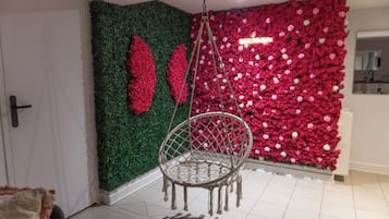 A room with a green wall, a red floral wall, and a hanging chair.