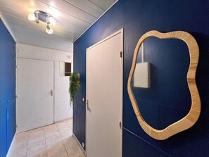 A hallway with a blue wall, a white door, and a mirror with a wooden frame.