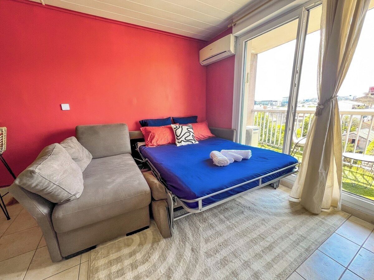 A room with a bed, a sofa, and a window with curtains.