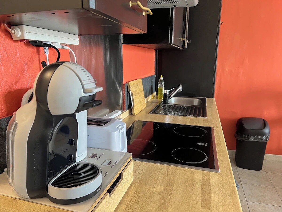 A compact kitchenette with a coffee maker, a toaster, a sink, and a stove.