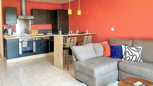 Ein kompakter Wohnbereich mit Küchenzeile, Essbereich und einer Sitzecke mit Sofa und Sesseln.