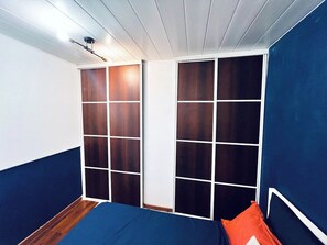Een kamer met een bed, een blauwe wand en een wit plafond.
