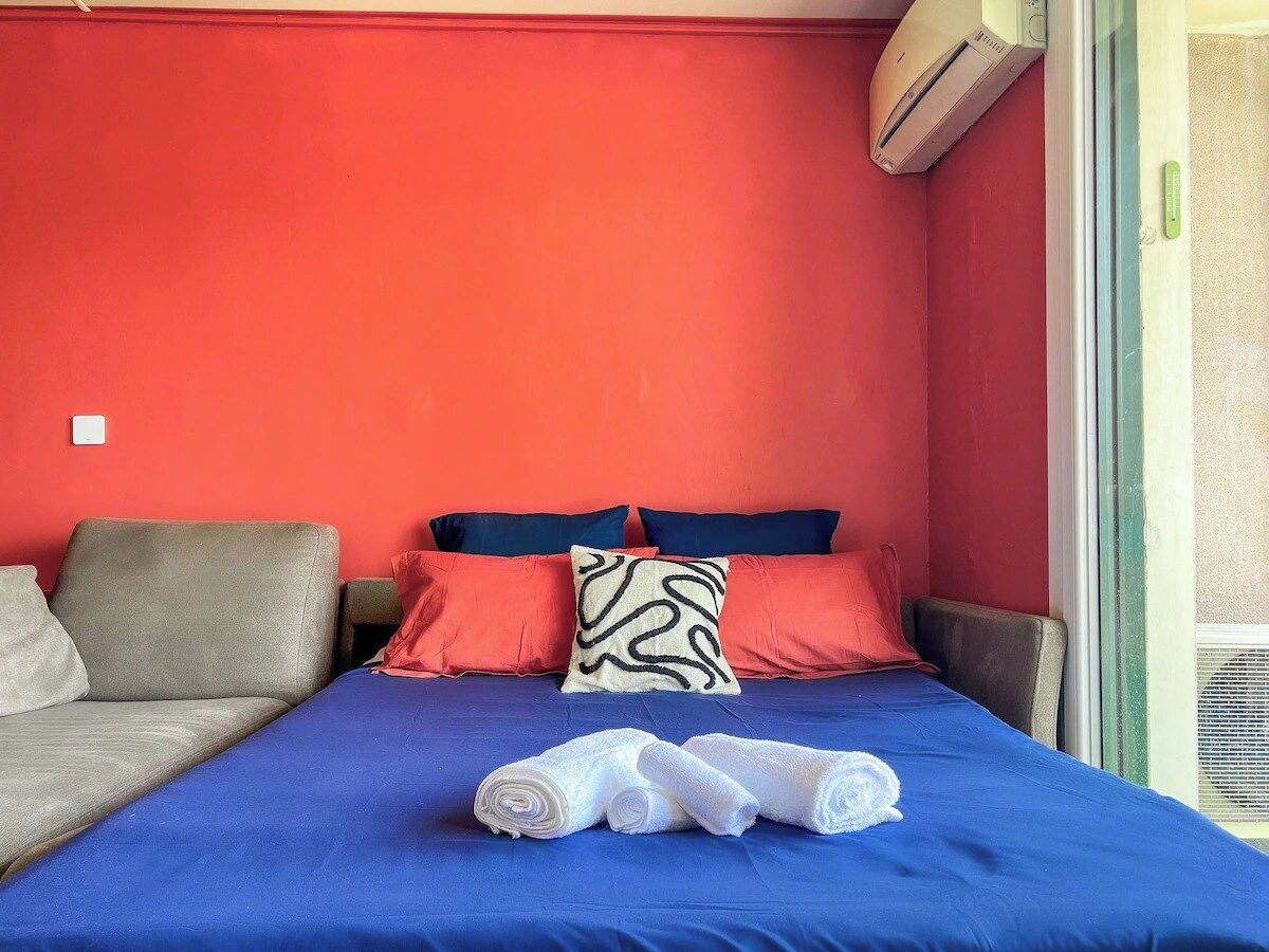 A room with a bed, a sofa, and an air conditioning unit.