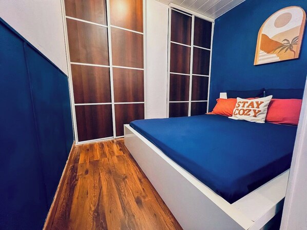 A bedroom with a bed, a wardrobe, and a wall-mounted artwork.