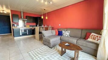 Un salon avec un canapé, une table basse et, au fond, un coin cuisine.