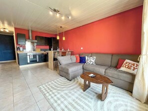 A living room with a sofa, a coffee table, and a kitchen area in the background.