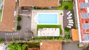 Vista aérea de una propiedad con piscina, mobiliario de exterior y jardín.