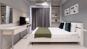 A modern bedroom with a bed, a desk, a TV, and a mirror. - LKN Residence (Bangkok)