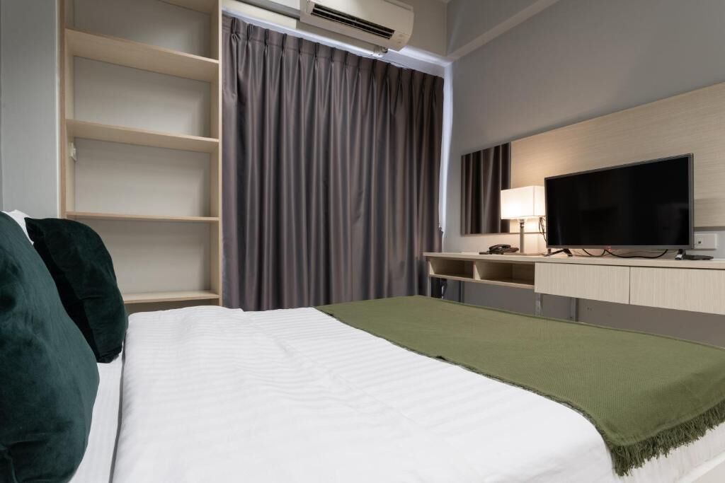 Una camera d'albergo con un letto, una televisione, una scrivania e un armadio.