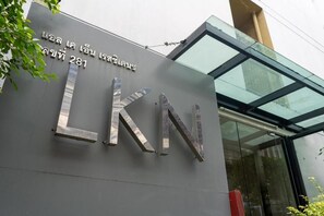 A building entrance with a large metallic sign displaying 'LKN' and a number '281'. - LKN Residence (Bangkok)