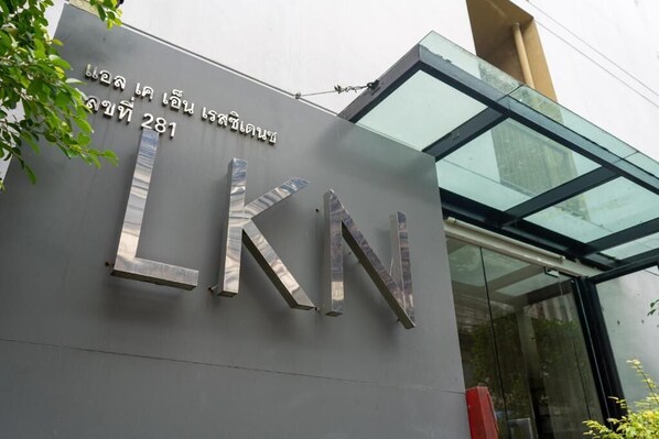 A building entrance with a large metallic sign displaying 'LKN' and a number '281'.