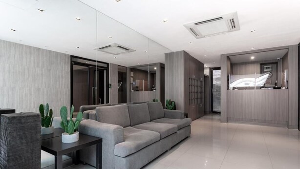A modern living room with a grey sofa, a dark wooden coffee table, and a potted plant. - LKN Residence (Bangkok)