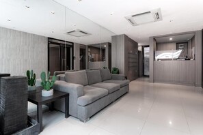 A modern living room with a grey sofa, a dark wooden coffee table, and a potted plant.