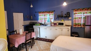 A compact kitchen with a stove, microwave, and sink. There is a dining table with chairs and a bed in the room. - Can sleep 7 people with private parking (Aeolus Valley)