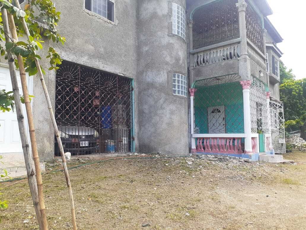 Een gebouw met twee verdiepingen, een balkon, een overdekte veranda en een garage.