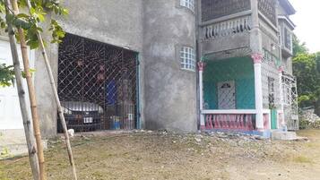 Een gebouw met twee verdiepingen, een balkon, een overdekte veranda en een garage.