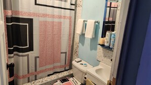 A bathroom with a shower curtain, a toilet, a sink with toiletries, and a mirror. - Can sleep 7 people with private parking (Aeolus Valley)