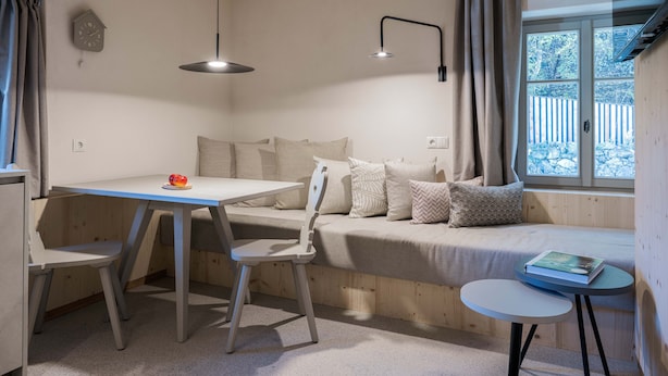 A cozy room with a wooden bench, a small table, and a chair.