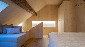 A cozy attic bedroom with a sloped ceiling, a built-in bed, a seating area with cushions, and a skylight.